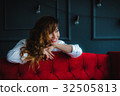 pretty brunette young woman posing behind red sofa 32505813
