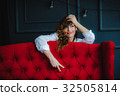 pretty brunette young woman posing behind red sofa 32505814