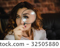 funny woman looking through a magnifying glass 32505880