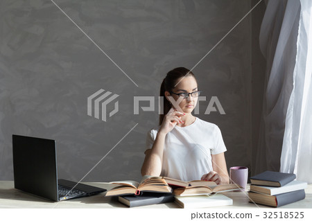 girl works at the computer reads a book at the 32518525
