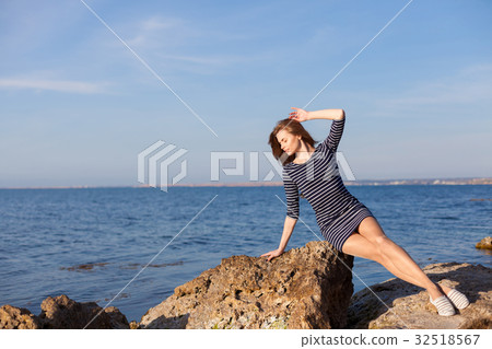girl sits on the rocky beach enjoys sunshine girl sits on the rocky beach enjoys sunshine 32518567