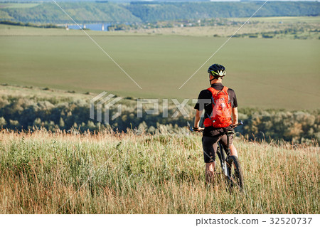 Rear view of the sportsman with his mountain bike Rear view of the sportsman with his mountain bike 32520737