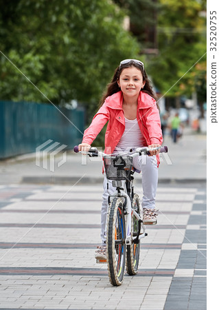 Cute kid girl in blue helmet going to ride her 32520755