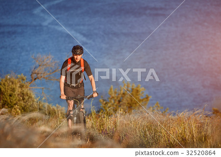 Young man riding mountain bike on the green meadow Young man riding mountain bike on the green meadow 32520864
