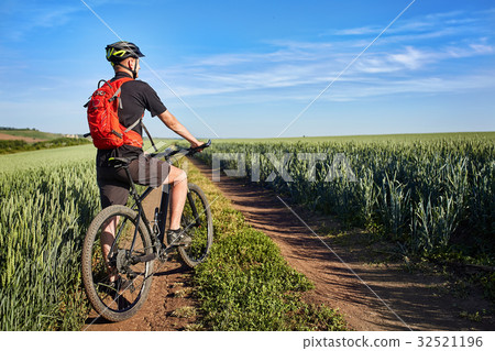 Young man riding on a bicycle on green meadow with 32521196