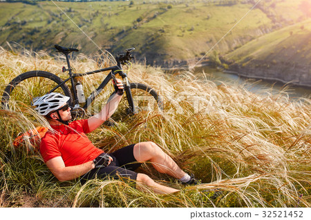 Mountain bike adventur. Cyclist has a rest on 32521452