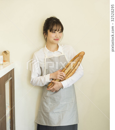 A woman with freshly baked French bread 32528295