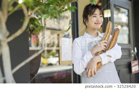 一個女人用新鮮出爐的法式麵包 一個女人用新鮮出爐的法式麵包 32528420