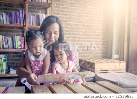 Mother and little daughter reading book together Mother and little daughter reading book together 32539653