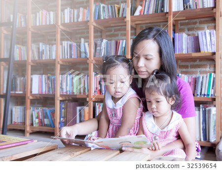 Mother and little daughter reading book together 32539654