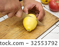 Male Hand with a knife cuts a ripe yellow lemon on 32553792