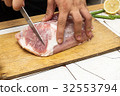 Cutting a piece of meat on a wooden cutting board 32553794