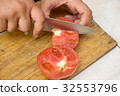 Slicing a ripe red tomato on a wooden cutting 32553796