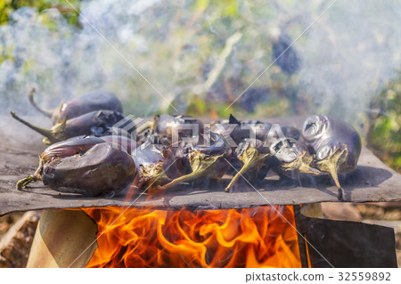 Eggplants cooking on a metal plate over open fire 32559892