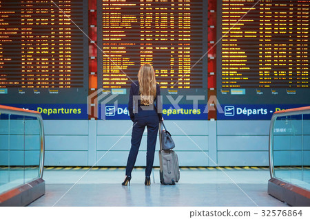 Woman with hand luggage in international airport terminal, looking at information board Woman with hand luggage in international airport terminal, looking at information board 32576864