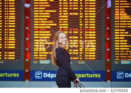 Woman with hand luggage in international airport terminal, looking at information board Woman with hand luggage in international airport terminal, looking at information board 32576888