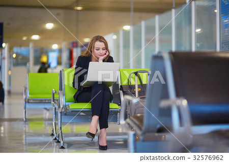 Woman in international airport terminal, working on her laptop 32576962