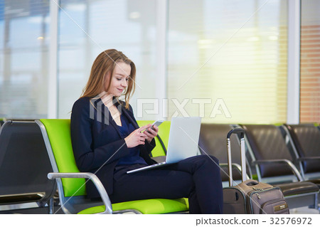 Woman in international airport terminal, checking her phone 32576972