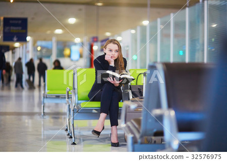 Woman in international airport terminal, reading book Woman in international airport terminal, reading book 32576975