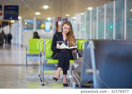 Business woman reading a book in international airport 32576977