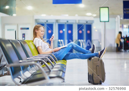 Young travelerin international airport checking her mobile phone 32576998