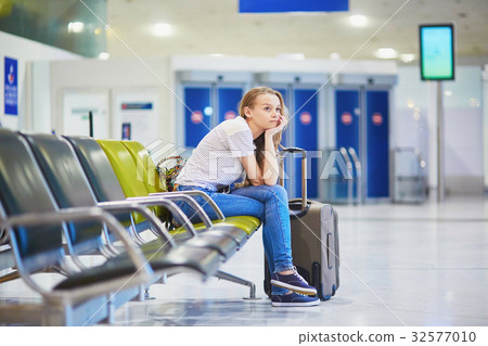 Tourist girl in international airport, waiting for her flight, looking upset Tourist girl in international airport, waiting for her flight, looking upset 32577010