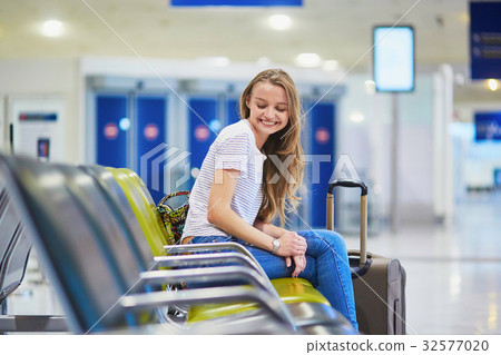 Tourist girl with backpack and carry on luggage in international airport, waiting for flight Tourist girl with backpack and carry on luggage in international airport, waiting for flight 32577020