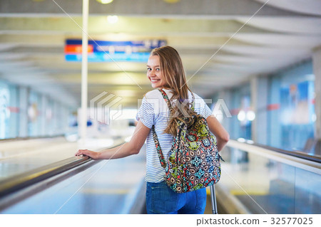 Tourist girl with backpack and carry on luggage in international Tourist girl with backpack and carry on luggage in international 32577025