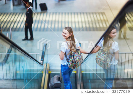Tourist girl with backpack and carry on luggage in international airport, on escalator 32577029