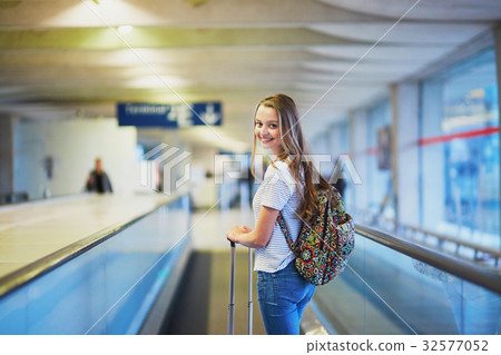 Beautiful young tourist girl with backpack and carry on luggage in international airport 32577052