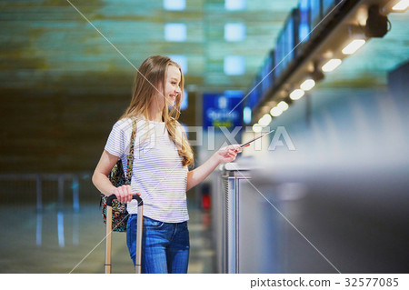 Beautiful young tourist girl in international airport at check-in counter Beautiful young tourist girl in international airport at check-in counter 32577085