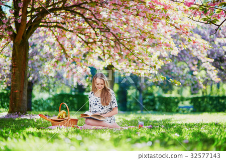 Beautiful young woman having picnic in blooming spring park 32577143