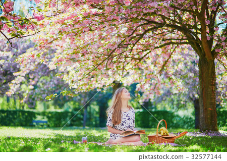 Beautiful young woman having picnic in blooming spring park Beautiful young woman having picnic in blooming spring park 32577144