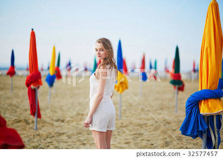 Beautiful young woman with famous colorful parasols on Deauville Beach 32577457