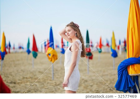 Beautiful young woman with famous colorful parasols on Deauville Beach 32577469