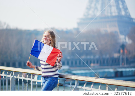 Beautiful young girl with French national flag near the Eiffel tower 32577612