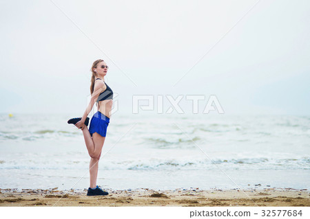 Woman on beach doing stretching exercise after a workout Woman on beach doing stretching exercise after a workout 32577684
