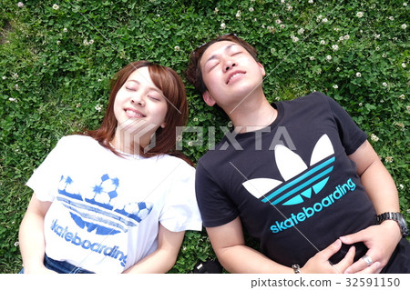 A couple lying down in the park A couple lying down in the park 32591150