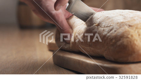 young man hands slicing ciabatta on cutting board young man hands slicing ciabatta on cutting board 32591828