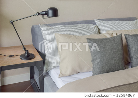 Gray and brown pillows on bed with reading lamp 32594867