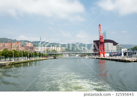 畢爾巴鄂的城市景觀沿著Nervión河站立的大型紅色起重機和遠離城市景觀的山脈 32595643
