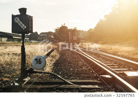 Railroad switch with train in the morning sun Railroad switch with train in the morning sun 32597765
