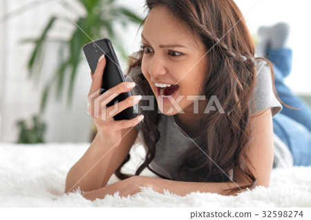 Beautiful young woman screaming on smartphone 32598274