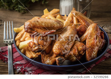 Baked chicken wings with french fries. 32599266