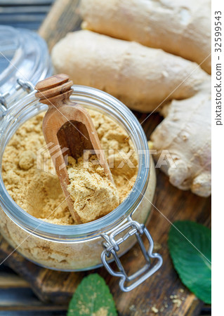 图库照片: ground ginger in a glass jar and ginger root.