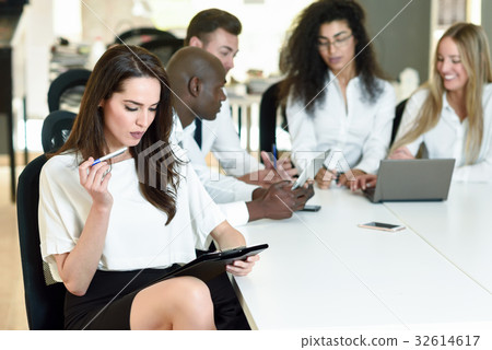 Multi-ethnic group of three businesspeople meeting in a modern o Multi-ethnic group of three businesspeople meeting in a modern o 32614617