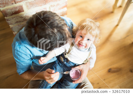Young father at home feeding his little son with Young father at home feeding his little son with 32617010