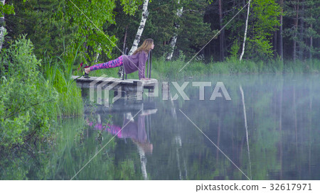 Young woman doing yoga exercises on the lake shore 32617971