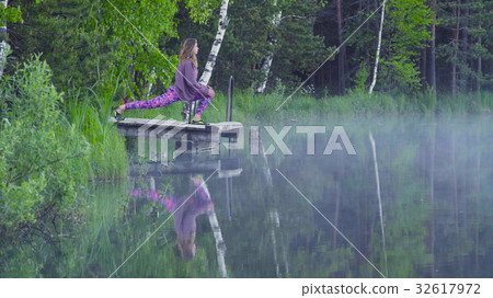 Young woman doing yoga exercises on the lake shore Young woman doing yoga exercises on the lake shore 32617972