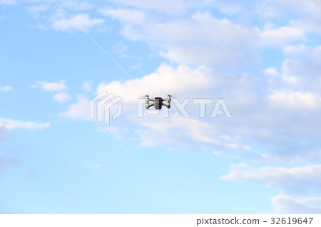 Quadcopter with camera flying on a clear sunny sky Quadcopter with camera flying on a clear sunny sky 32619647
